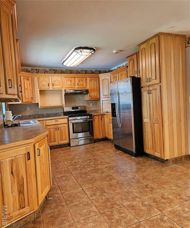 1504 Dean Ave, Hannibal, MO 63401 - kitchen featuring stainless steel appliances, under cabinet range hood, tasteful backsplash, dark countertops, and tile patterned floors