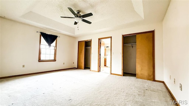 200 April Dr, Saint Robert, MO 65584 - unfurnished bedroom with a tray ceiling, multiple closets, light carpet, a textured ceiling, and a ceiling fan