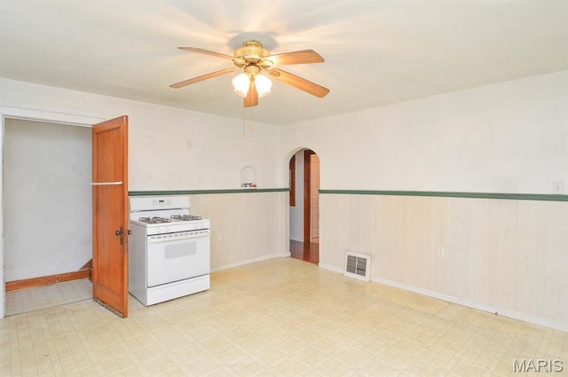 307 S S St, Smithton, IL 62285 - kitchen with white gas range oven, arched walkways, ceiling fan, light floors, and a wainscoted wall