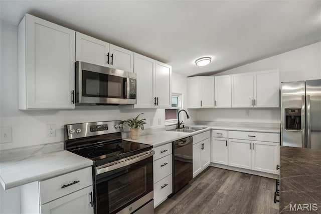 16 Garrett Ln, Defiance, MO 63341 - kitchen featuring appliances with stainless steel finishes, vaulted ceiling, dark wood-style floors, and white cabinetry