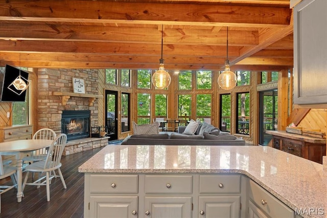 2506 Alpine Woods Dr, Wright City, MO 63390 - kitchen featuring open floor plan, beamed ceiling, dark wood-style flooring, a stone fireplace, and light stone countertops