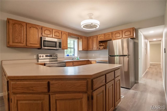 116 Buttry Ln, Wappapello, MO 63966 - kitchen with appliances with stainless steel finishes, light countertops, a peninsula, light wood-style flooring, and brown cabinets