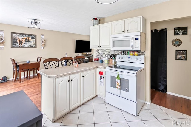 7800 Chuck Ct, Godfrey, IL 62035 - kitchen with white appliances, a peninsula, white cabinets, tasteful backsplash, and light countertops