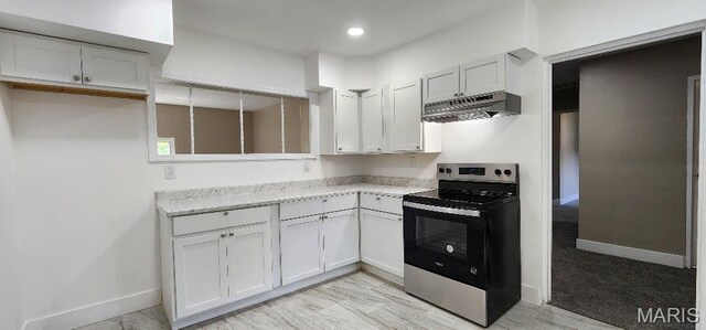 115 N 5th St, De Soto, MO 63020 - kitchen with electric stove, under cabinet range hood, white cabinetry, and recessed lighting