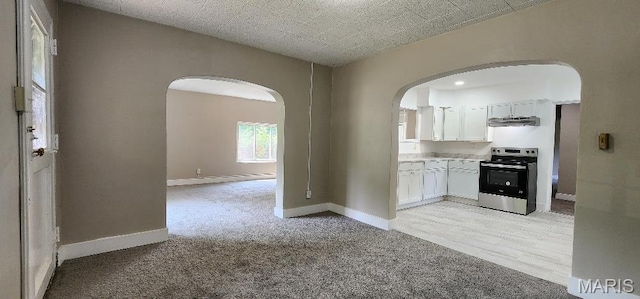 115 N 5th St, De Soto, MO 63020 - kitchen featuring electric range, arched walkways, ventilation hood, and light colored carpet
