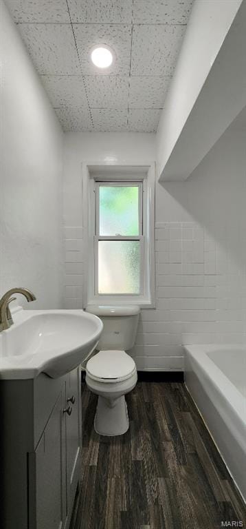 115 N 5th St, De Soto, MO 63020 - full bath with a tub, wood finished floors, vanity, and tile walls