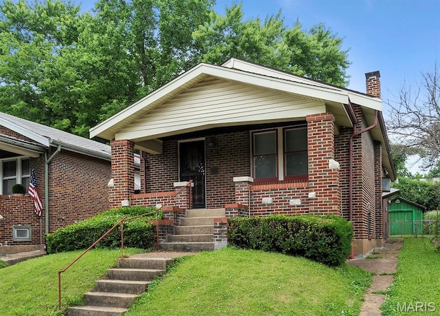 887 Wall St, Saint Louis, MO 63147 - bungalow featuring a chimney, brick siding, covered porch, and a front yard