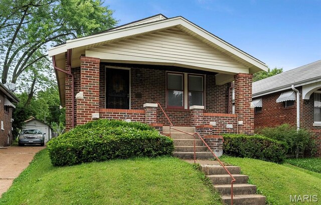 887 Wall St, Saint Louis, MO 63147 - bungalow with concrete driveway, brick siding, a front yard, and a detached garage