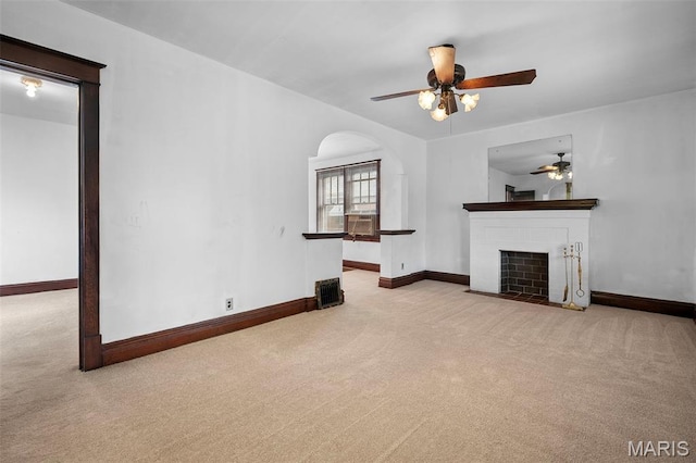887 Wall St, Saint Louis, MO 63147 - unfurnished living room featuring carpet floors, a ceiling fan, a fireplace with flush hearth, and arched walkways