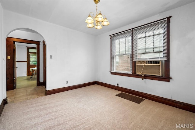 887 Wall St, Saint Louis, MO 63147 - spare room featuring arched walkways, light carpet, a chandelier, and healthy amount of natural light