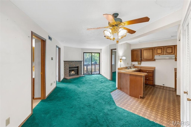 1514 Summer Run Dr Unit 208, Florissant, MO 63033 - kitchen featuring brown cabinetry, under cabinet range hood, ceiling fan, open floor plan, and a fireplace