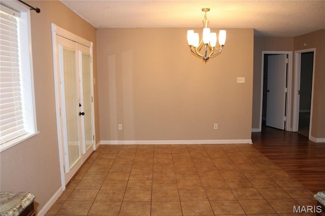 17576 Rigdon St, Kennett, MO 63857 - unfurnished room with a chandelier, a textured ceiling, healthy amount of natural light, and light tile patterned floors