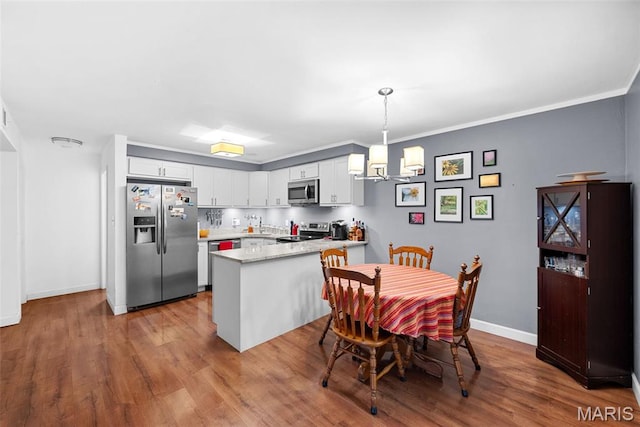 1400 Heritage Lndg Unit 109, Saint Charles, MO 63303 - kitchen featuring stainless steel appliances, a peninsula, white cabinets, wood finished floors, and a chandelier