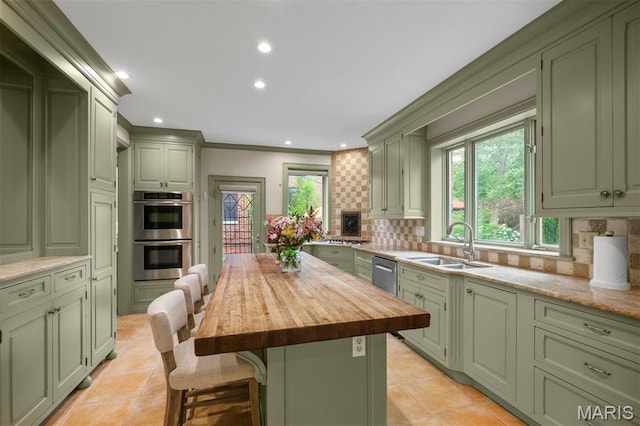20 Ridgemoor Dr, Clayton, MO 63105 - kitchen featuring green cabinetry, appliances with stainless steel finishes, butcher block countertops, backsplash, and a kitchen bar