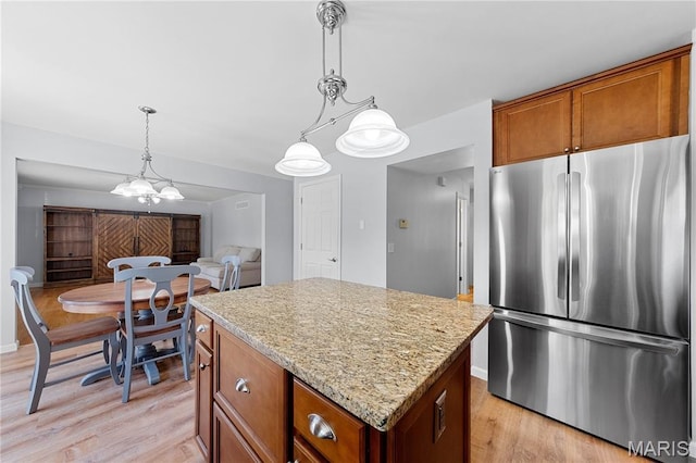 3924 Cambridge Crossing Dr, Saint Charles, MO 63304 - kitchen featuring freestanding refrigerator, a center island, brown cabinets, and light wood-style flooring