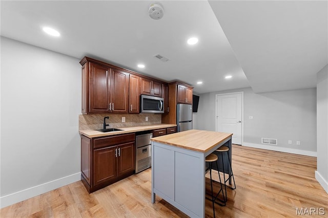 3924 Cambridge Crossing Dr, Saint Charles, MO 63304 - kitchen featuring stainless steel appliances, a breakfast bar, backsplash, light wood-style floors, and recessed lighting