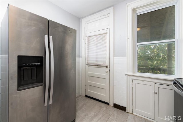 6162 W Park Ave, Saint Louis, MO 63139 - kitchen with stainless steel fridge with ice dispenser, light countertops, light tile patterned floors, and a wainscoted wall