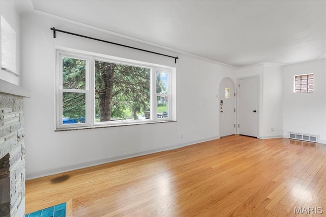 5660 Oleatha Ave, Saint Louis, MO 63139 - unfurnished living room with a fireplace, plenty of natural light, light wood-style floors, and arched walkways