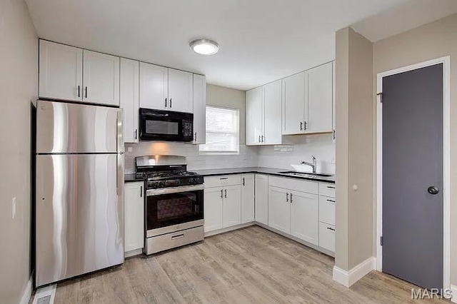 675 Pimlico Dr, Florissant, MO 63033 - kitchen with stainless steel appliances, dark countertops, light wood-type flooring, and white cabinets