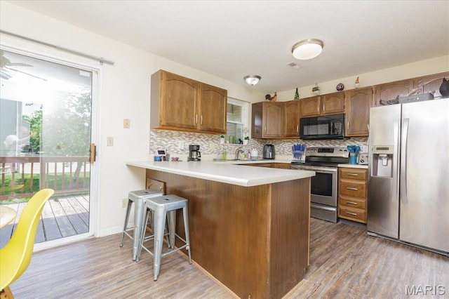 23 Trailside Ct Unit 2, Saint Peters, MO 63303 - kitchen with appliances with stainless steel finishes, light wood-style flooring, a peninsula, and decorative backsplash