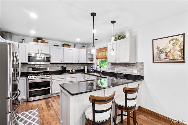 13345 Iberg Rd, Highland, IL 62249 - kitchen with appliances with stainless steel finishes, a peninsula, wood finished floors, decorative backsplash, and recessed lighting