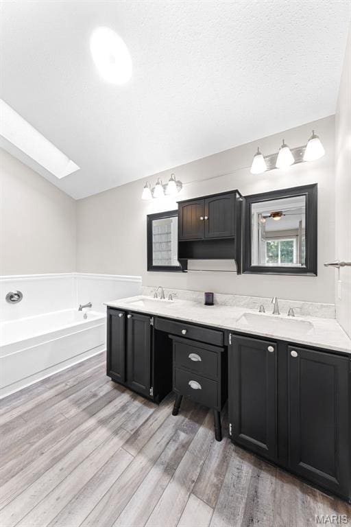 856 Hemingway Ln Unit D, Weldon Spring, MO 63304 - bathroom with double vanity, wood finished floors, a skylight, and a garden tub
