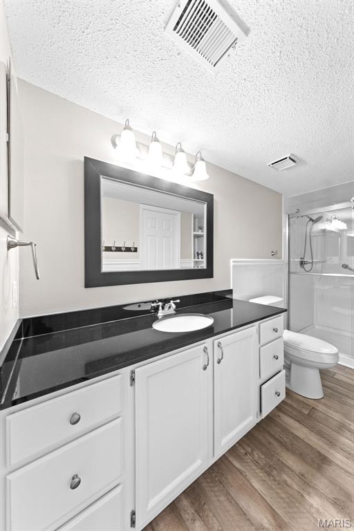 856 Hemingway Ln Unit D, Weldon Spring, MO 63304 - full bath with vanity, wood finished floors, a shower with shower door, and a textured ceiling
