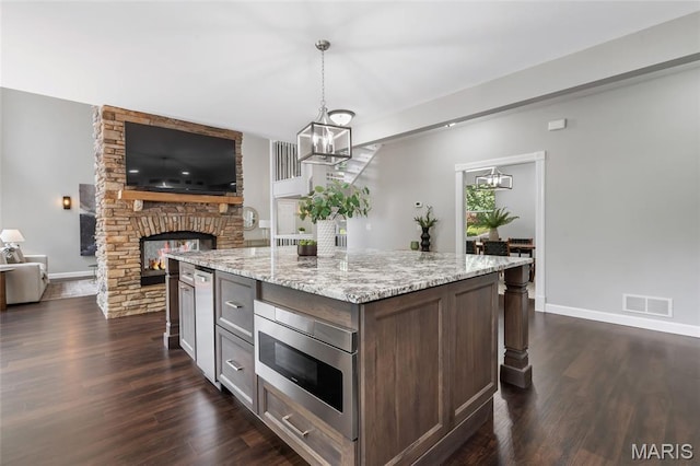 3516 Hawthorne Ridge Dr, Eureka, MO 63025 - kitchen featuring stainless steel microwave, a fireplace, open floor plan, dark wood-style flooring, and light stone counters