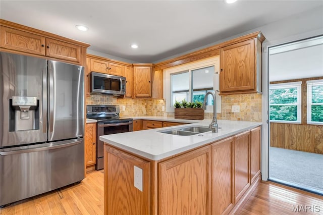 5701 State Road P, De Soto, MO 63020 - kitchen with appliances with stainless steel finishes, a peninsula, light countertops, light wood-type flooring, and tasteful backsplash
