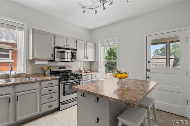5524 Devonshire Ave, Saint Louis, MO 63109 - kitchen with stainless steel appliances, light tile patterned floors, a breakfast bar, a center island, and tasteful backsplash