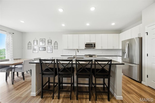 213 Dell View Dr, Arnold, MO 63010 - kitchen featuring stainless steel appliances, wood finished floors, a kitchen bar, an island with sink, and recessed lighting