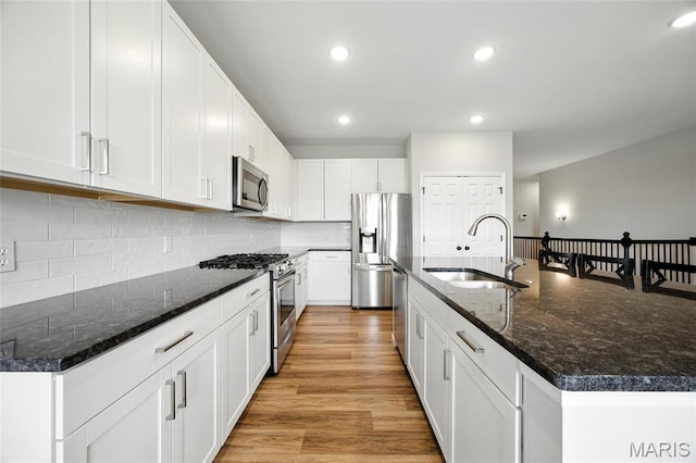 213 Dell View Dr, Arnold, MO 63010 - kitchen featuring appliances with stainless steel finishes, light wood-type flooring, a center island with sink, white cabinets, and recessed lighting