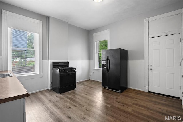 3921 Pennsylvania Ave, Saint Louis, MO 63118 - kitchen with black appliances, wood finished floors, and a wainscoted wall