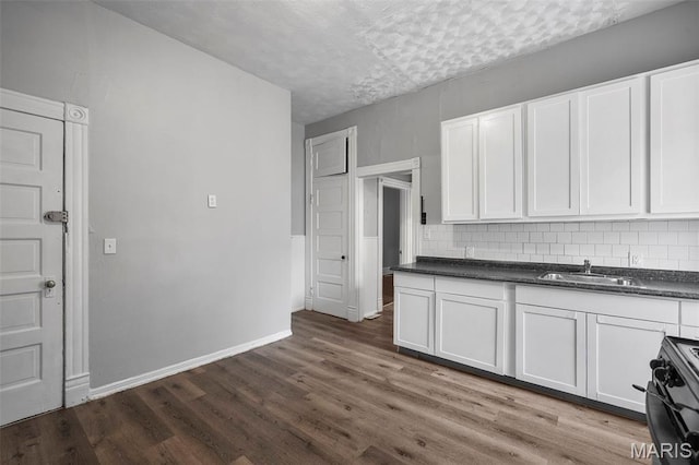 3921 Pennsylvania Ave, Saint Louis, MO 63118 - kitchen with range, dark countertops, dark wood-style floors, white cabinets, and decorative backsplash