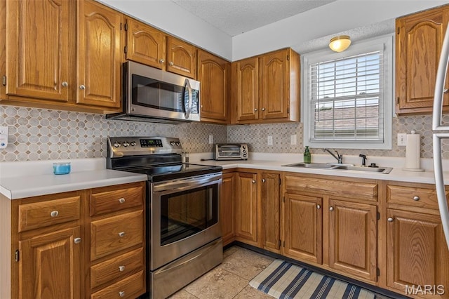 1531 Charmaine Dr, Bonne Terre, MO 63628 - kitchen featuring stainless steel appliances, light countertops, brown cabinets, light tile patterned flooring, and a textured ceiling