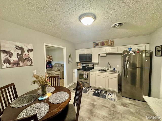 119 N Saint Charles St, Bowling Green, MO 63334 - kitchen featuring stainless steel appliances, white cabinetry, light countertops, and a textured ceiling