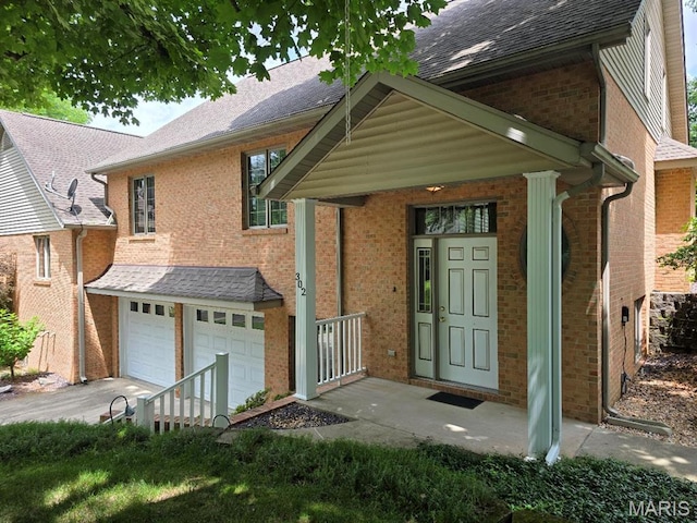 302 Lorean St, Troy, IL 62294 - doorway to property with brick siding, a garage, concrete driveway, and roof with shingles