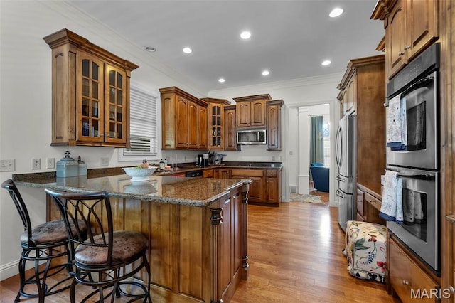 2528 Palomino Dr, Cape Girardeau, MO 63701 - kitchen featuring appliances with stainless steel finishes, a peninsula, crown molding, a breakfast bar, and brown cabinets