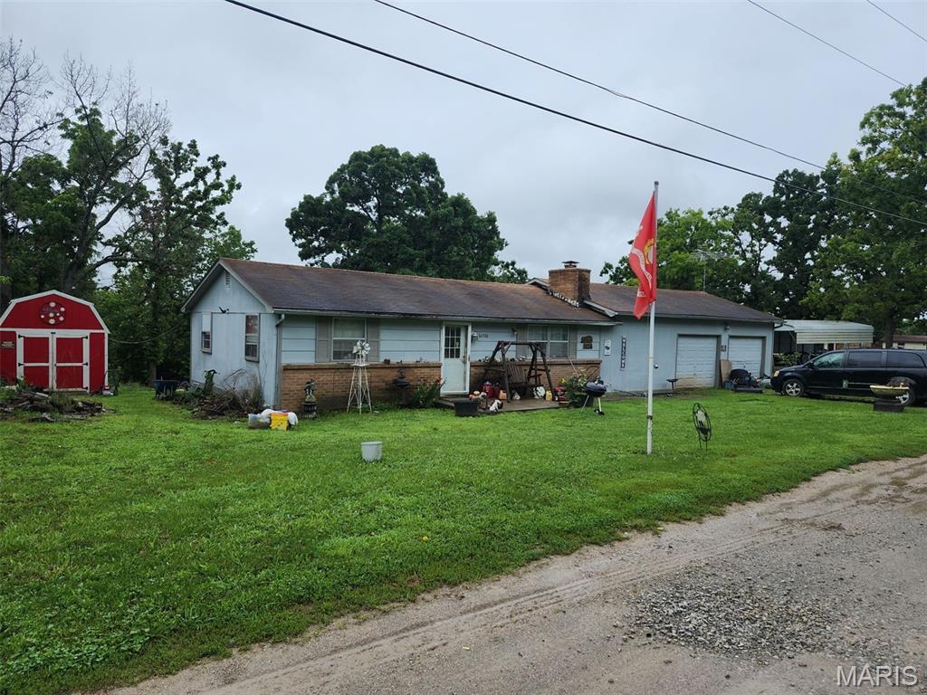 26006 Sarong Dr Unit 16, Edwards, MO 65326 - view of front of property featuring a front yard, brick siding, a storage unit, a garage, and a chimney