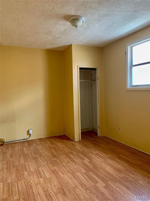 5811 Helen Ave, Jennings, MO 63136 - unfurnished bedroom with light wood finished floors, a textured ceiling, and a closet