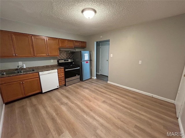 6023 Shillington Dr, Berkeley, MO 63134 - kitchen featuring appliances with stainless steel finishes, under cabinet range hood, light wood finished floors, brown cabinets, and a textured ceiling