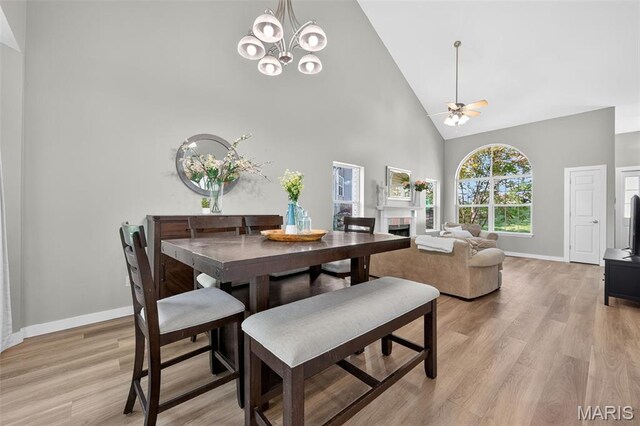 794 Buckboard Ln, Fenton, MO 63026 - dining room featuring high vaulted ceiling, light wood-style flooring, ceiling fan, a chandelier, and a fireplace