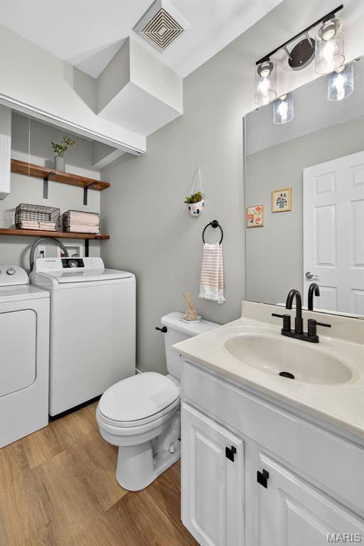 794 Buckboard Ln, Fenton, MO 63026 - bathroom featuring washing machine and dryer, wood finished floors, and vanity