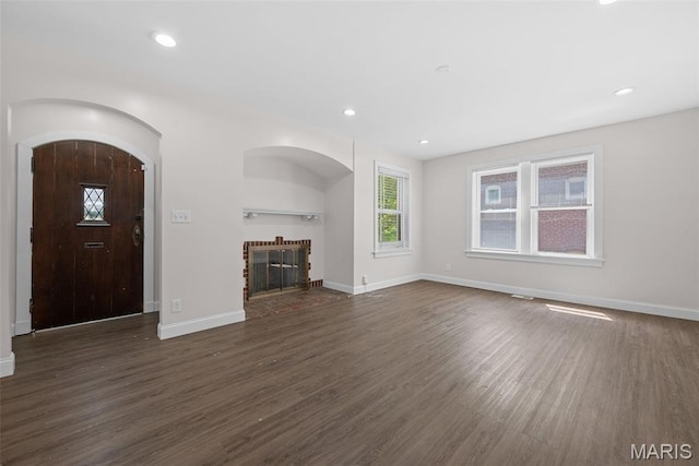 8260 Glen Echo Dr, Bel-Nor, MO 63121 - unfurnished living room with dark wood-style flooring, a fireplace, recessed lighting, and arched walkways