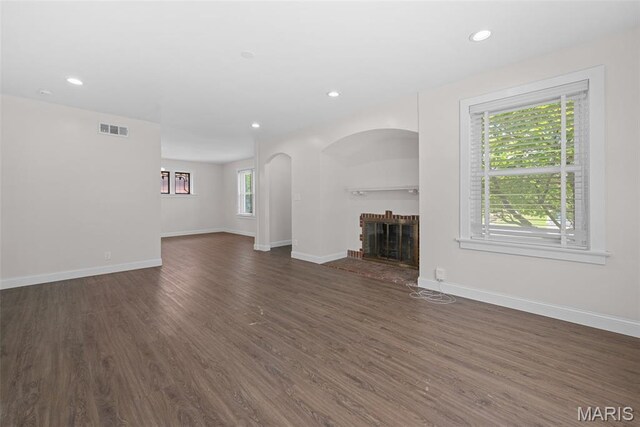 8260 Glen Echo Dr, Bel-Nor, MO 63121 - unfurnished living room with a fireplace, dark wood-type flooring, arched walkways, and recessed lighting