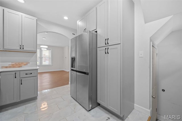 8260 Glen Echo Dr, Bel-Nor, MO 63121 - kitchen featuring stainless steel fridge, arched walkways, light countertops, recessed lighting, and gray cabinets