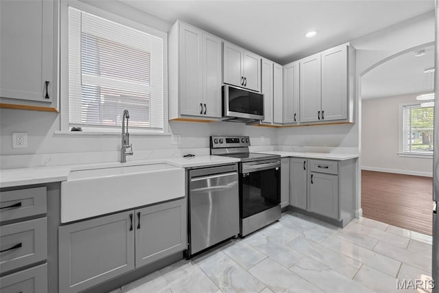 8260 Glen Echo Dr, Bel-Nor, MO 63121 - kitchen with stainless steel appliances, gray cabinets, arched walkways, recessed lighting, and light stone counters