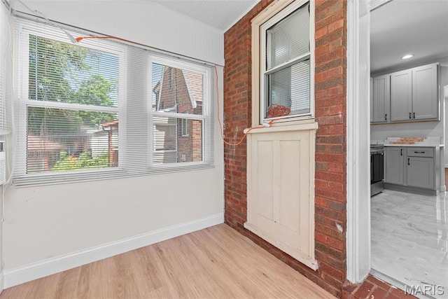 8260 Glen Echo Dr, Bel-Nor, MO 63121 - empty room featuring plenty of natural light, light wood-type flooring, and brick wall
