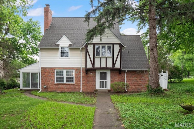 1931 Elm St, Saint Charles, MO 63301 - tudor house featuring a chimney, a front lawn, and brick siding