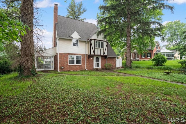 1931 Elm St, Saint Charles, MO 63301 - tudor-style house with brick siding, a chimney, a front lawn, and a sunroom